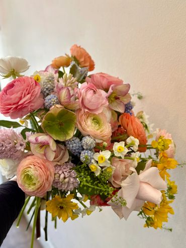 A vibrant bouquet with various colorful flowers against a plain wall.