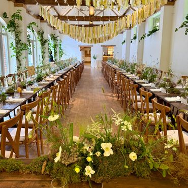 Elegant banquet hall decorated with yellow ribbons and floral centerpieces.