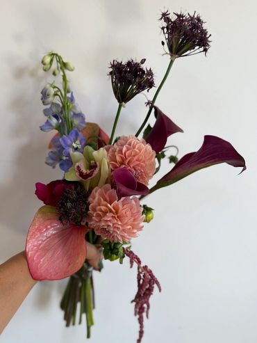 Hand holding a bouquet of colorful flowers.