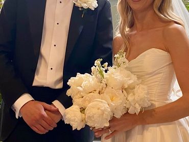 Bride and groom in wedding attire holding a bouquet.
