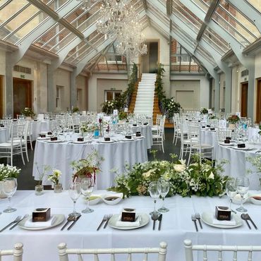Elegant wedding reception setup with white decor and floral arrangements.