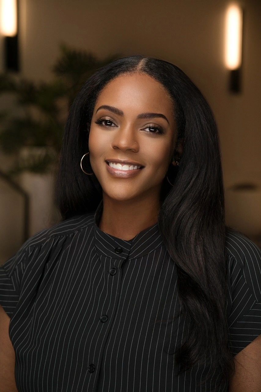 Smiling woman with long hair wearing a black striped shirt.