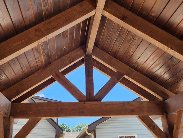 Wooden roof structure with triangular design under clear blue sky.