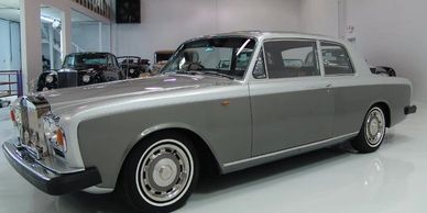 Classic silver Rolls-Royce luxury car in a showroom.