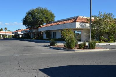 Empty strip mall with clear blue sky and desert landscaping.