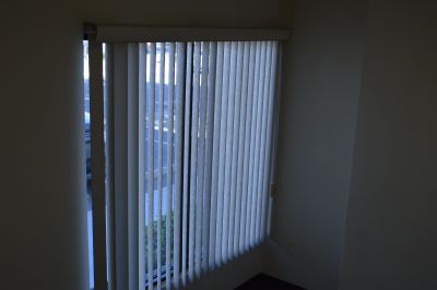 Vertical blinds covering a window with sunlight filtering through.