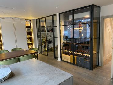 Modern dining area with glass wine storage and stylish shelving.