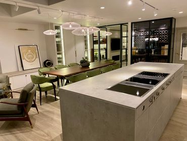 Modern kitchen with concrete island and dining area.