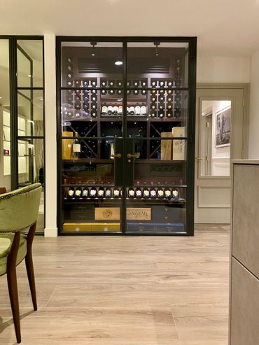 Modern wine cellar with glass doors and wooden shelves.