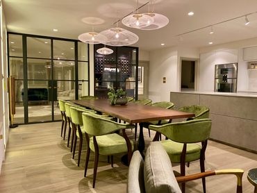 Modern dining room with green chairs and elegant lighting.
