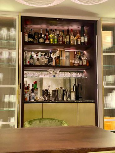 A stylish home bar with liquor bottles and glassware.