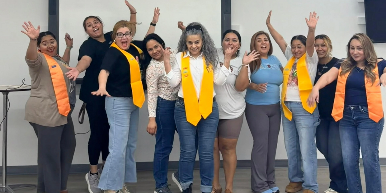 Group of women celebrating with yellow stoles in a classroom setting.