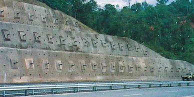 Concrete retaining wall with embedded anchors along a highway.