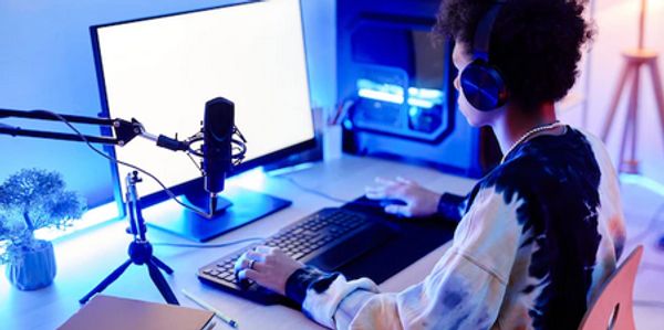 Person wearing headphones using a computer with a microphone setup.