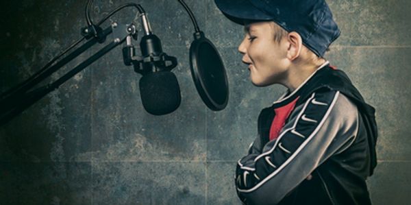 A boy recording vocals in a studio setup with a microphone.