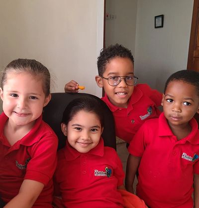 Four kids smiling, wearing red shirts.
