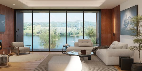 Modern living room with large glass windows overlooking a serene lake and greenery.