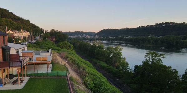 River view with houses and greenery at sunset.