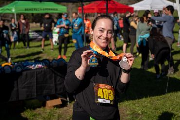 Woman proudly holding a race medal.