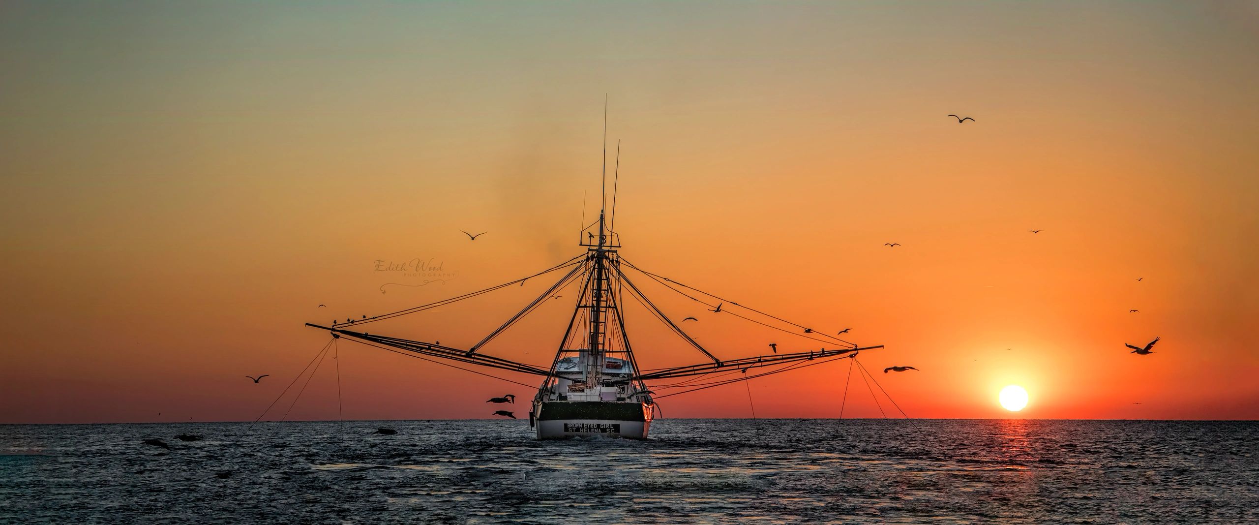 Boat sailing at sunset over the ocean.