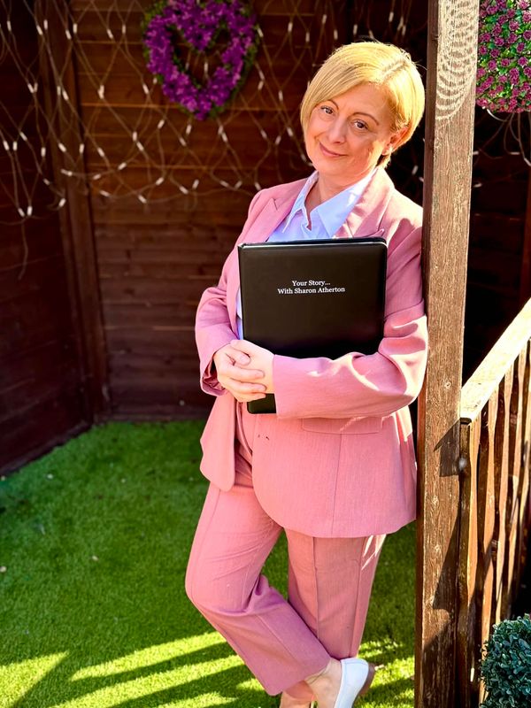 Woman in pink suit holding folder outside.
