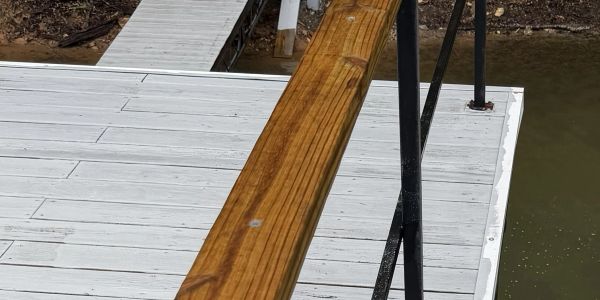 Wooden dock and railing by water.