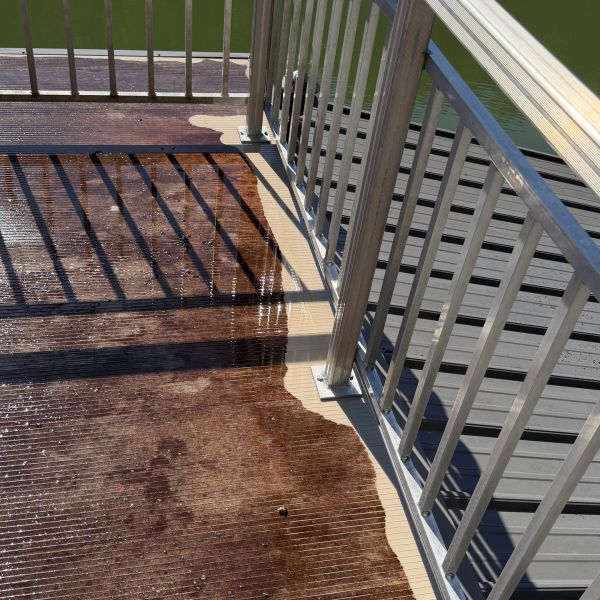 Wet and dry wooden deck with metal railing and shadows.