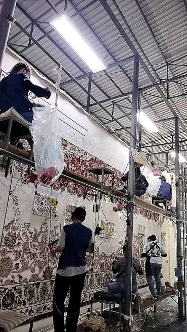 คนงานกำลังทอและทำงานบนพรมใหญ่
