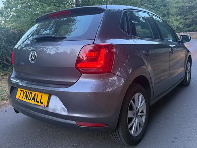 Gray Volkswagen hatchback on a road near trees.