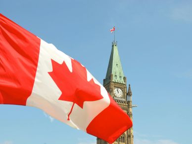 Canadian flag waving in front of the Peace Tower on Parliament Hill.