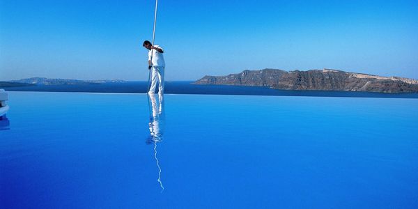 Service Technician Cleaning 🧹 infinity edge Swimming Pool on seaside cliff