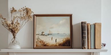 Dried flowers, artwork and books arranged tastefully on a mantlepiece