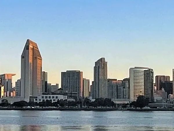 San Diego skyline at sunrise with calm waters reflecting buildings.
