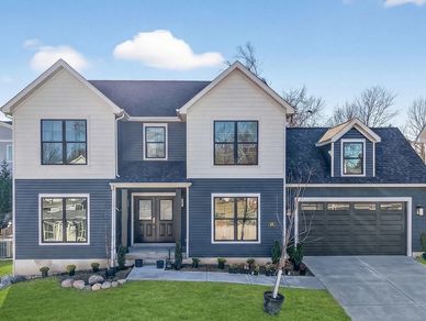 Contemporary two-story home with navy and cream siding, black-trimmed windows, covered entry with do