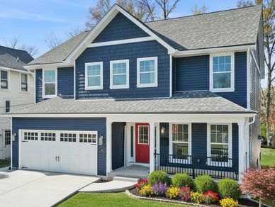A modern blue two-story house with a red door and manicured front lawn.
