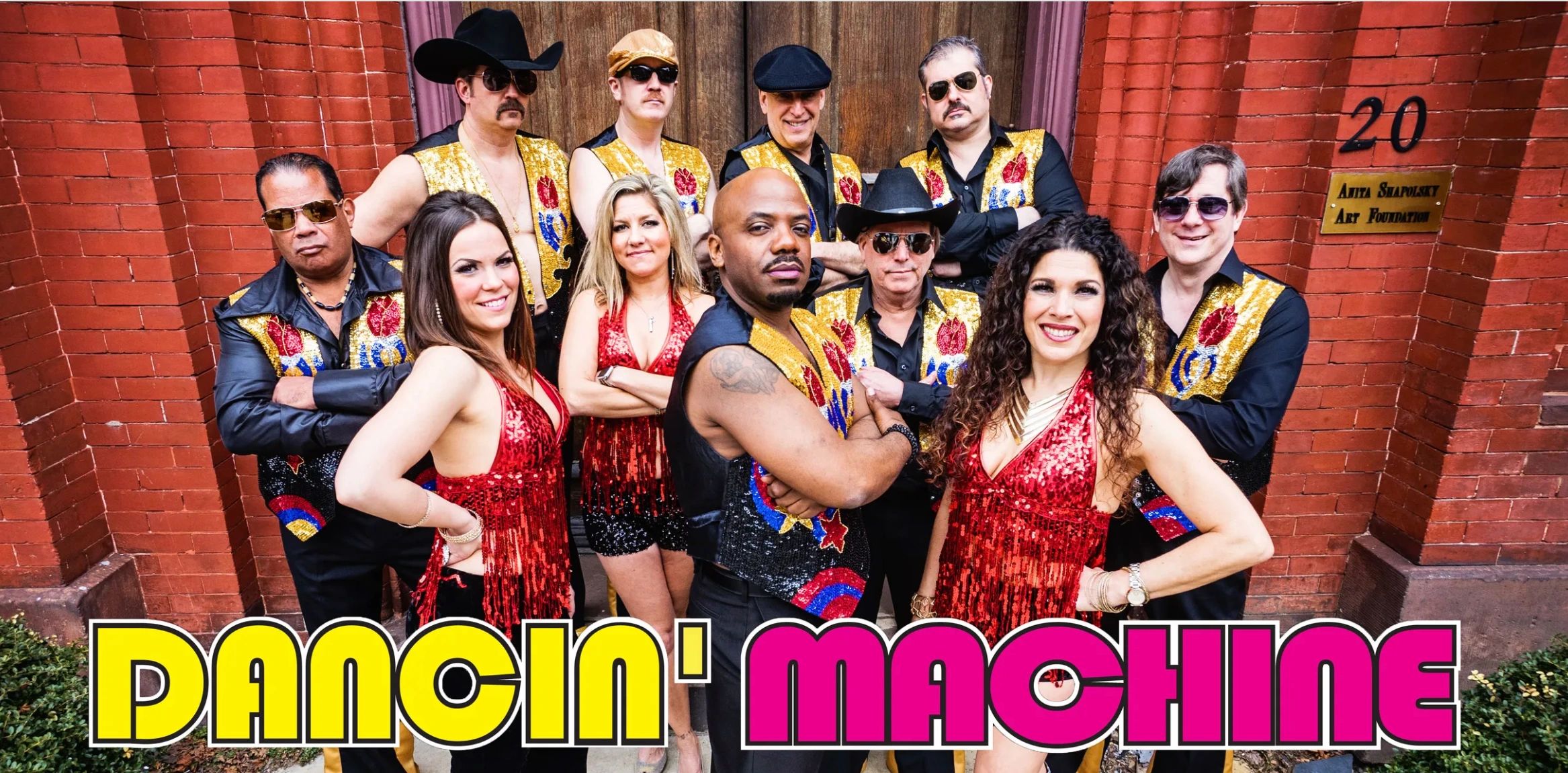 A vibrant dance group in matching costumes pose together.