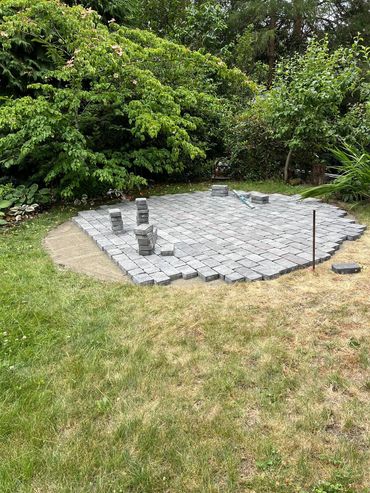 A garden area with a partially paved stone patio under construction.