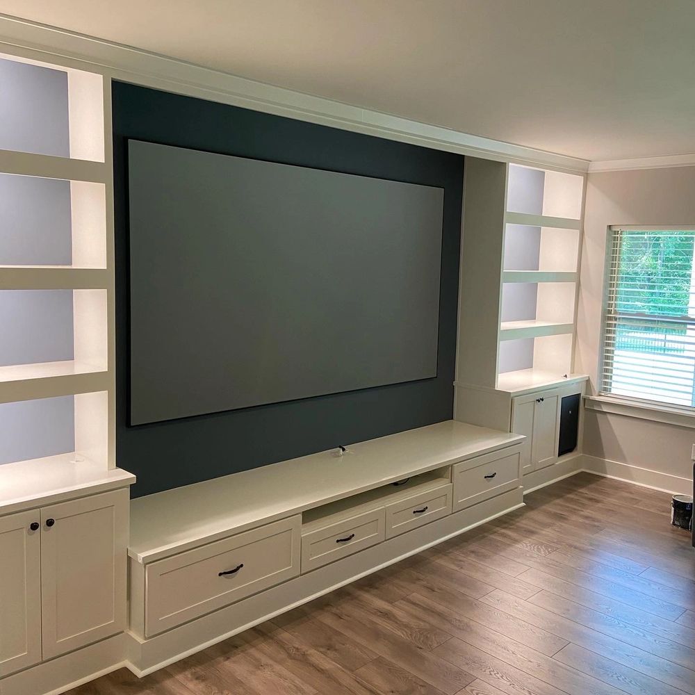 Custom built-in movie room with integrated sound bar cubby, subwoofer cabinets, and dimmable light.