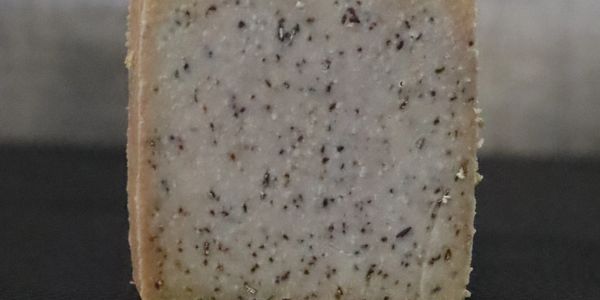Square piece of speckled soap on a black surface.