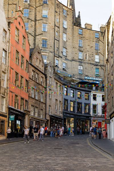 Historic street with cobblestones and colorful buildings bustling with pedestrians.