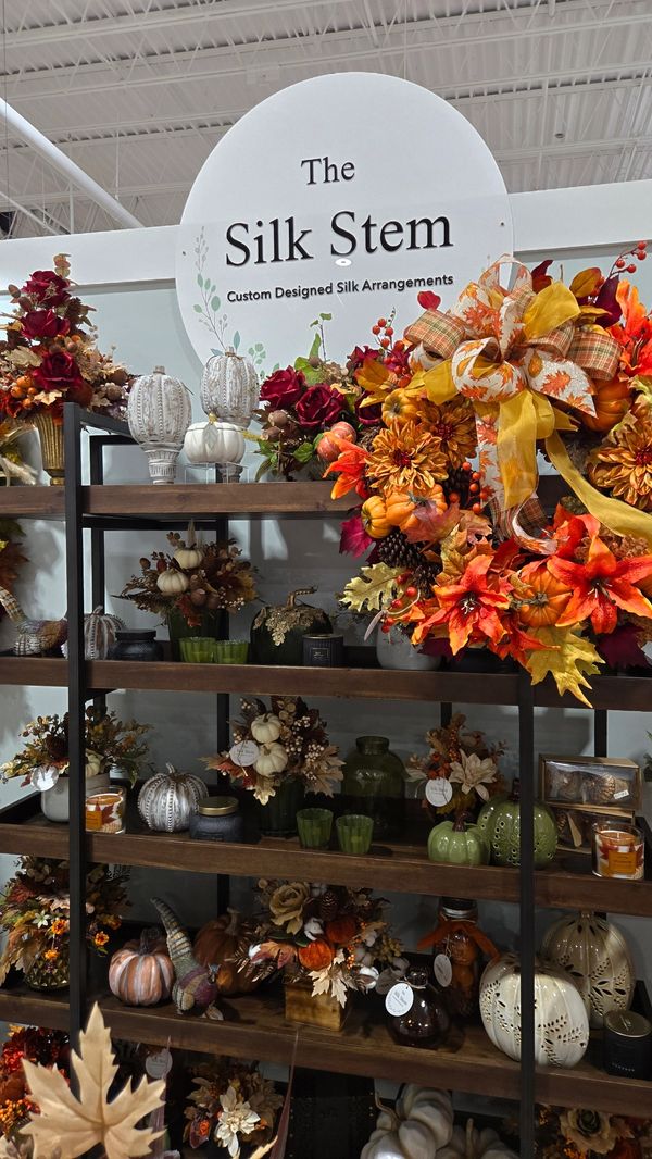 Decorative harvest wreath with pumpkins, autumn foliage, and gold ribbon