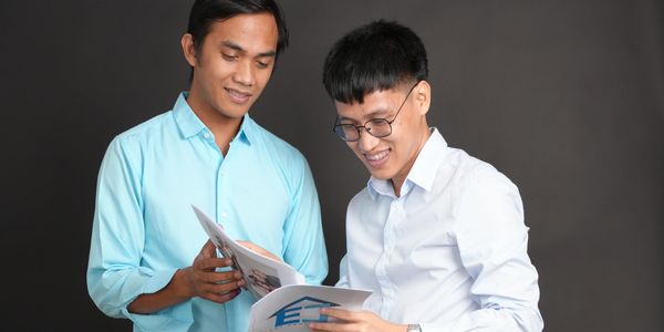 Two professionals reviewing property management and real estate documents on a laptop in a modern, casual office setting, highlighting stress-free ownership solutions and seamless real estate services.
