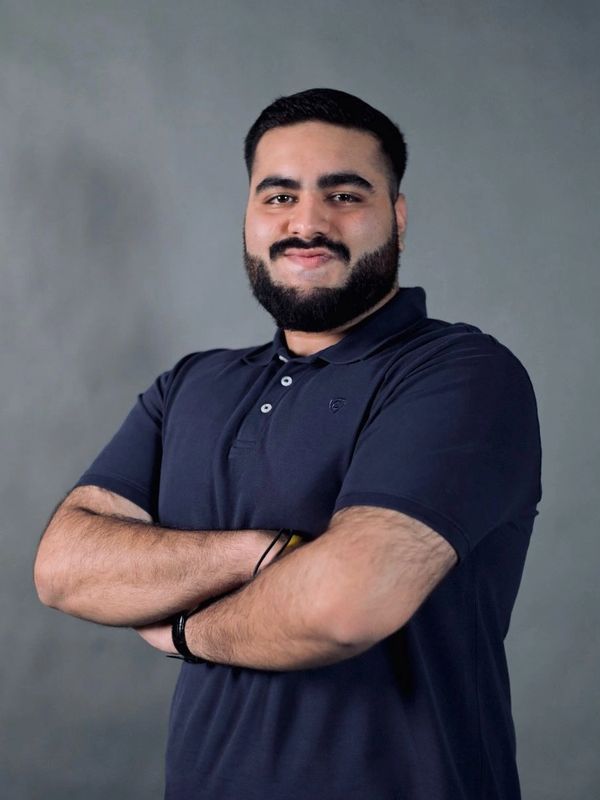 Confident man with beard and crossed arms in a navy blue polo shirt.