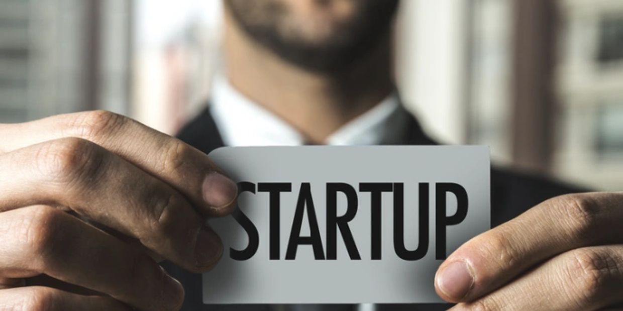 A man in a suit holding a card that says STARTUP.