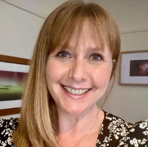 Woman in her 40's with long light brogn hair and blue eyes wearing black and white flowery dress, sm