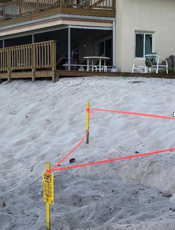 Beach area roped off with warning signs near a residential building.