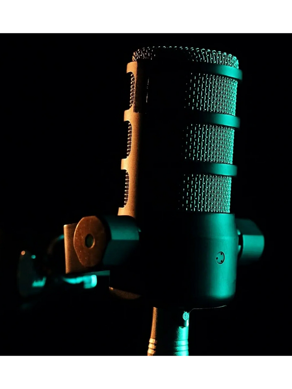 Close-up of a studio microphone with moody blue and orange lighting.
