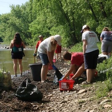 Volunteers cleaning a riverside area collecting trash.