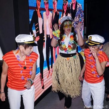 Three people in nautical and tropical-themed costumes dancing indoors.