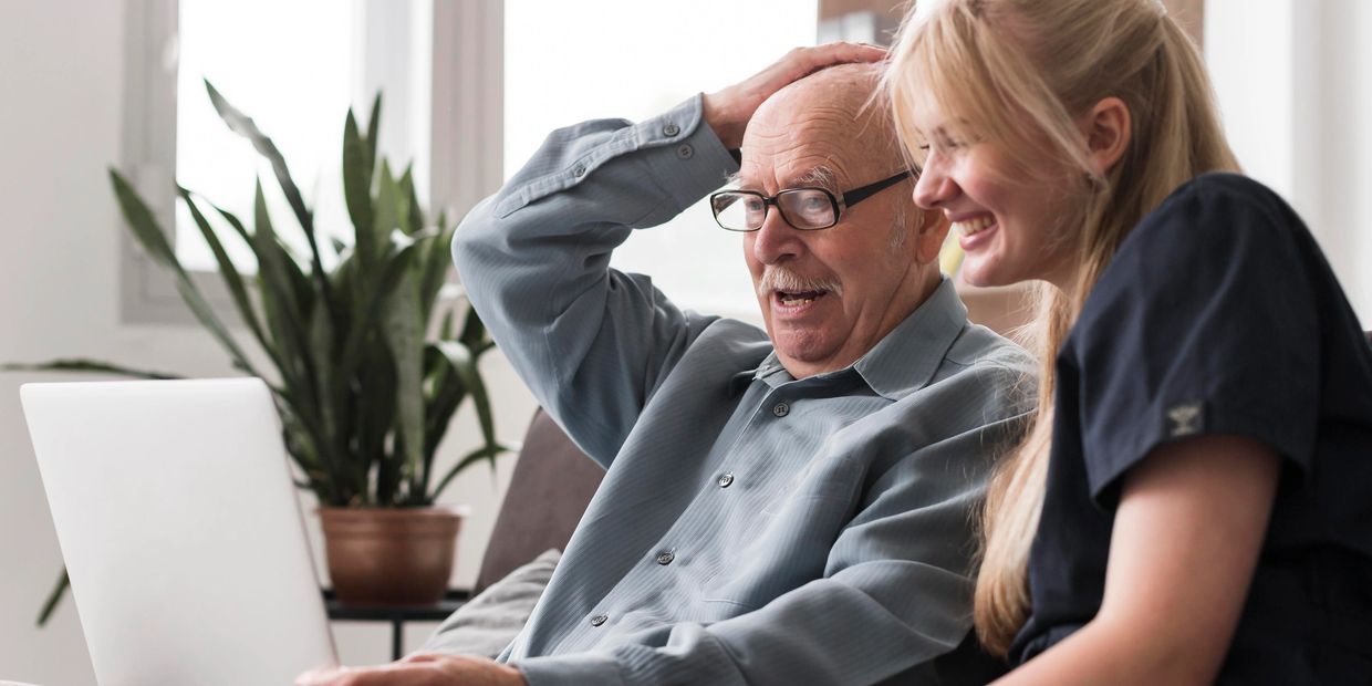 A Caretaker with an elderly person showing activities in laptop